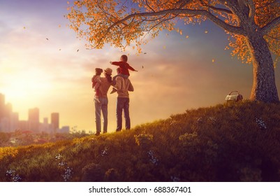 Happy family at sunset. Father, mother and two children daughters having fun and playing on autumn nature. The child is sitting on the shoulders of his father. - Powered by Shutterstock