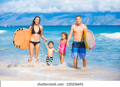 Happy Family With Surfboards On The Beach In Hawaii