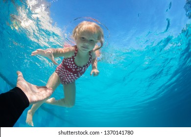 Happy Family In Swimming Pool. Child Jump Deep Down In Pool With Fun - Dive Underwater To Reach Extended Hand. Healthy Lifestyle, People Water Sport Activity, Swimming Lessons On Holidays With Kids