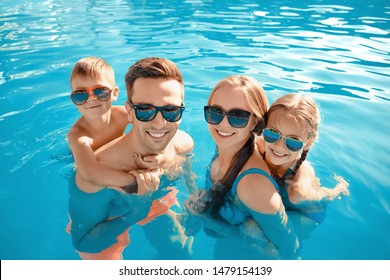 Happy Family In Swimming Pool On Summer Day