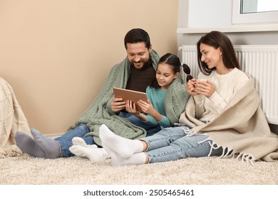 Happy family with tablet near heating radiator at home - Powered by Shutterstock