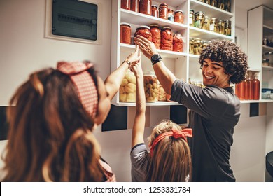 A happy family takes jars with pickled vegetables from the pantry shelf. - Powered by Shutterstock