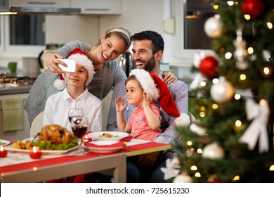 Happy Family Taking Selfie At Decorated Christmas Table With Tasty Food