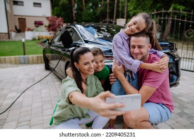 Happy Family Taking Selfie, Waiting For Electric Car Charging.