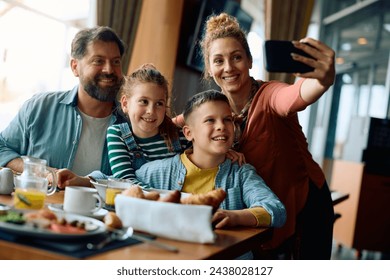 Happy family taking selfie while having breakfast in restaurant during their hotel stay. - Powered by Shutterstock