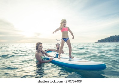 Happy Family Teaching The Daughter To Stand On The Surf In The Ocean. Concept About Family, Sport, Active People