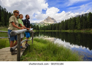 Happy family with teenager taking brake during trekking day on Dolomites mountain in summer time in Italy. Concept of travel, friendly family.