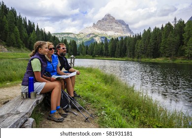 Happy family with teenager taking rest tee brake during trekking day on Dolomites mountain in summer time in Italy. Concept of travel, friendly family.