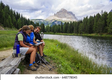 Happy Family With Teenager Taking Rest Tee Brake During Trekking Day On Dolomites Mountain In Summer Time In Italy. Concept Of Travel, Friendly Family.