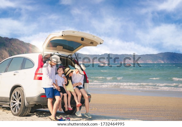 Happy family they are sitting in the\
family car and having fun to tease each other at the sunny day on\
the peaceful beach.  Concept happy family on\
vacation.