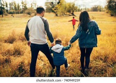 Família feliz e eles filhos andando no parque outono e ter um bom tempo