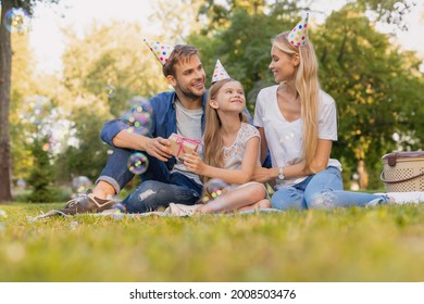 Happy Family Of Three Celebrating Birthday Party In The Park. Happy Birthday! Celebration Event With Greetings And Gifts Presents Outdoors On A Picnic In Wood Forest