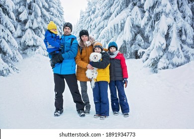 Happy Family With Three Children And Puppy Dog, Hiking In Mountains Wintertime, Lots Of Snow, Beautiful Winter Forest