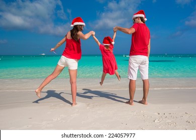 Happy Family Of Three In Christmas Hats During Tropical Vacation