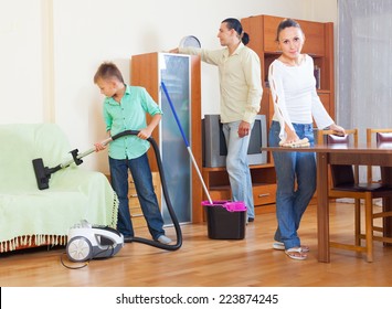 Happy family of three cleaning with vacuum cleaner in home