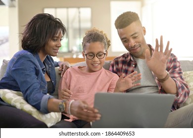 Happy family of three connected with laptop to communicate with relatives