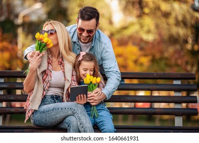 Happy Family Of Three Having Fun Together Outdoor.Family,lifestyle And Technology Concept.Spring Day In The Park.