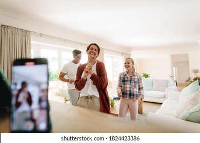 Happy family of three having fun at home creating videos for their social media. Family making dance videos to share on social media - Powered by Shutterstock