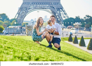 Happy Family Of Three Near The Eiffel Tower And Enjoying Their Vacation In Paris, France