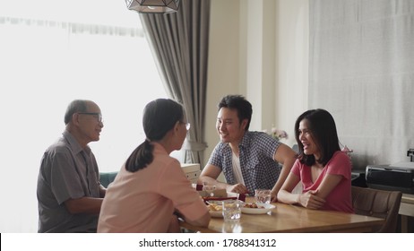 Happy Family Time And Relationship, Asian Big Family Having Small Party Together At Home. Pan Shot Of Elder Couple With Son And Daughter Talking With Fun And Smile Having Dinner On Dining Table.