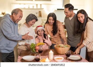 Happy Family Time And Relationship, Asian Big Family Having Small Christmas Party Eating Food Together At Home. Kid Is Happy To See Parent, Cousin Preparing Food And Bring It To Dining Table At Home.