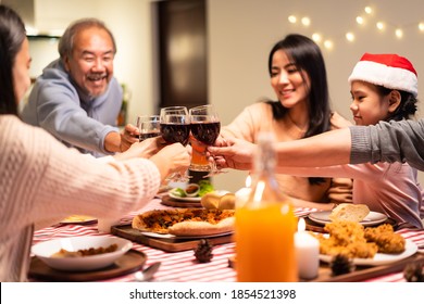 Happy Family Time And Relationship, Asian Big Family Having Christmas Party Eating Food Together At Home. Grandparent Is Happy To See His Child, Nephew Eating And Clinking Glass On Dining Table.