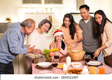 Happy Family Time And Relationship, Asian Big Family Having Small Christmas Party Eating Food Together At Home. Kid Is Happy To See Parent, Cousin Preparing Food And Bring It To Dining Table At Home.