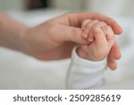 Happy family. Tiny newborn infant baby little hand on mother hand palm. Newborn baby holding parent finger after birth. Mom baby at home. Support protection of new life. Handle with care