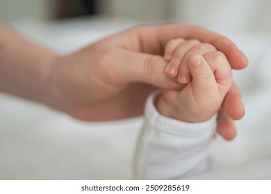 Happy family. Tiny newborn infant baby little hand on mother hand palm. Newborn baby holding parent finger after birth. Mom baby at home. Support protection of new life. Handle with care