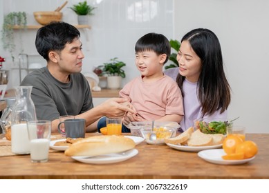 Happy Family Together. Asian Parent Eating Breakfast With Little Son In The Kitchen.