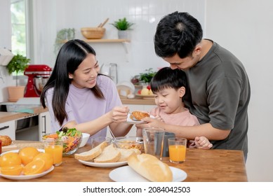 Happy Family Together. Asian Parent Eating Breakfast With Little Son In The Kitchen.