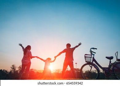 Happy family together, parents with their little child at sunset. Father raising baby up in the air. - Shutterstock ID 654559342