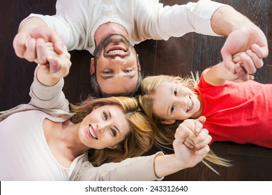 Happy family together. Top view of happy family of three bonding to each other and smiling while lying on the hardwood floor  - Powered by Shutterstock