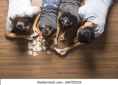 Happy Family Top View Lying On Floor With Solving A Jigsaw Puzzle Problem And Enjoying Their Leisure Time Activities.  In Her Room At Home