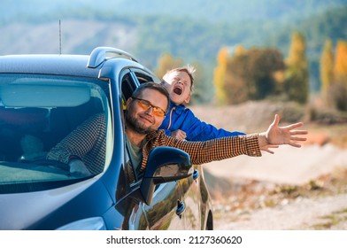 Happy family travel by car in the mountains. Summer vacation concept. Happy boy and father looking out from auto window and greets nature. Breathing clean air