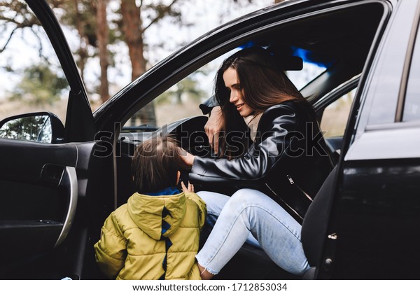 Happy family travel by car in the\
forest. Beautiful woman with a child of 3 years in the car are\
going to have a trip. Spring or fall vacation\
concept.