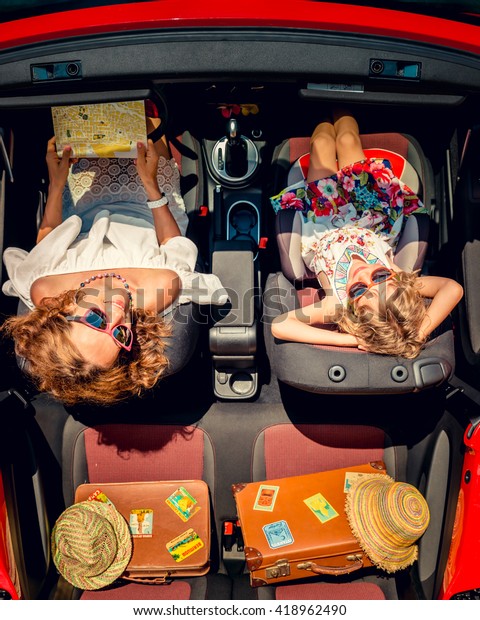 Happy family\
travel by car. Woman and child having fun in red cabriolet. Summer\
vacation and travel concept. Top\
view