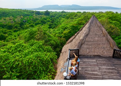 Happy Family Travel, Explore Menjangan Rainforest Near Pemuteran. Mother, Kids Relax On Lounge Veranda With Tropical Jungle View. Walking Day Tour, Activity In Adventure Camp On Bali Summer Vacation.