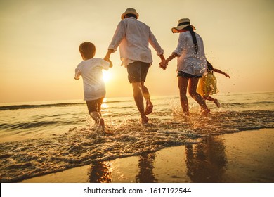 Happy family travel on beach in holiday, outdoor activity on summer vacations. Silhouette of a happy family enjoying the evening play on the beach.