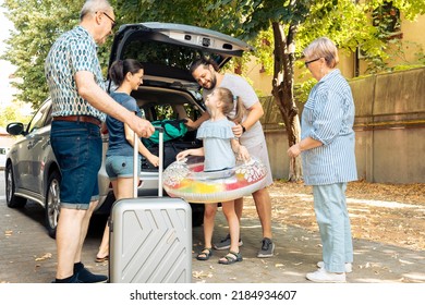 Happy family travelling at seaside with car, leaving on vacation trip with parents, grandparents and small girl. Loading luggage and suitcase in automobile trunk, summer adventure. - Powered by Shutterstock