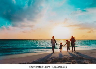 glückliche Familie mit drei Kindern, die am Sonnenuntergang entlang gehen