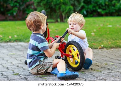 Happy family of two brothers: Funny little sibling  boys repairing bicycle wheel in summer, outdoors. Selective focus. - Powered by Shutterstock