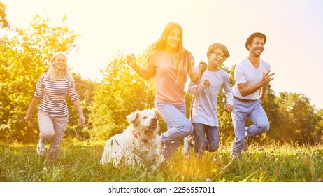 Happy family with two children and dog running around in the garden in summer - Shutterstock ID 2256557011
