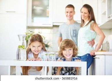 Happy Family And Two Children In Kitchen With Fresh Lime Water