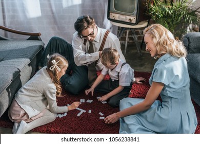 Happy Family With Two Children Playing Dominoes Together At Home, 1950s 