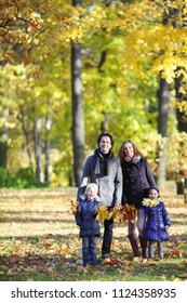 Happy family with two children walking in autumn park holding hands
