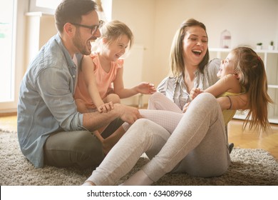 Happy family with two daughters playing at home. Family sitting on floor and playing together. - Shutterstock ID 634089968