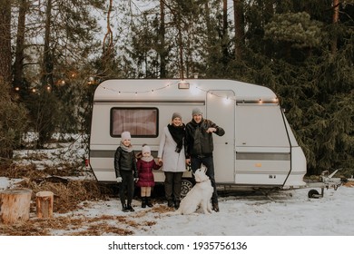 Happy Family With Two Kid Daughters Standing In Front Of Caravan With Dog. Safe Travel Concept In Pandemic Situation. Domestic Family Travel Concept. Camper Van Affordable Travel In All Seasons