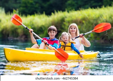 Happy Family With Two Kids Enjoying Kayak Ride On Beautiful River. Mother With Little Girl And Teenager Boy Kayaking On Hot Summer Day. Water Sport Fun. Canoe And Boat For Children.