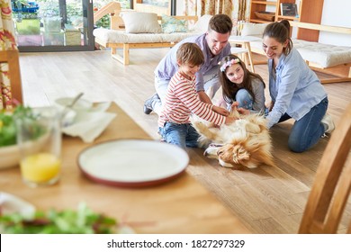 Happy Family And Two Kids Play With The Dog In The Living Room